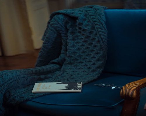 A comfortable armchair with a blanket and a book resting on it