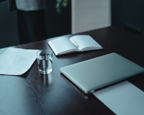 A notebook, pen, and a glass of water on a modern office desk