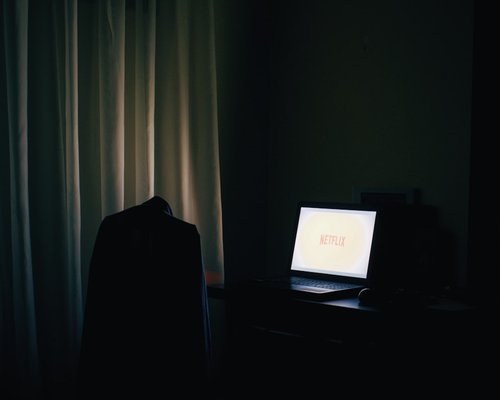 A person closing a laptop at the end of the day in a dimly lit room